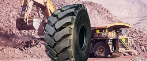 A giant, rugged offroad tire for heavy machinery, isolated in a rocky mining landscape